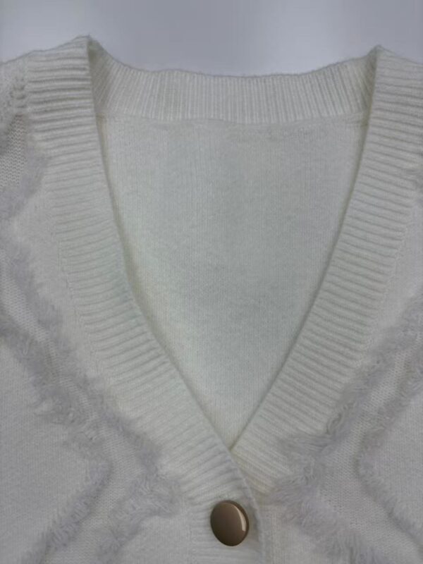 Close-up of a white knit cardigan with a V-neck and a single button, showcasing detailed knitting and soft fabric suitable for stylish casual wear.
