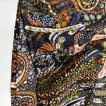 Close-up of vibrant paisley and floral fabric with intricate designs in orange, blue, green, and pink colors, showcasing detailed textile craftsmanship.