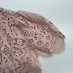 Close-up of delicate pink lace fabric with intricate patterns, ideal for fashion and apparel design, showcasing craftsmanship and fine textile details.
