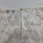 Close-up of intricate lace embroidery on a wedding dress with a delicate button closure at the back.
