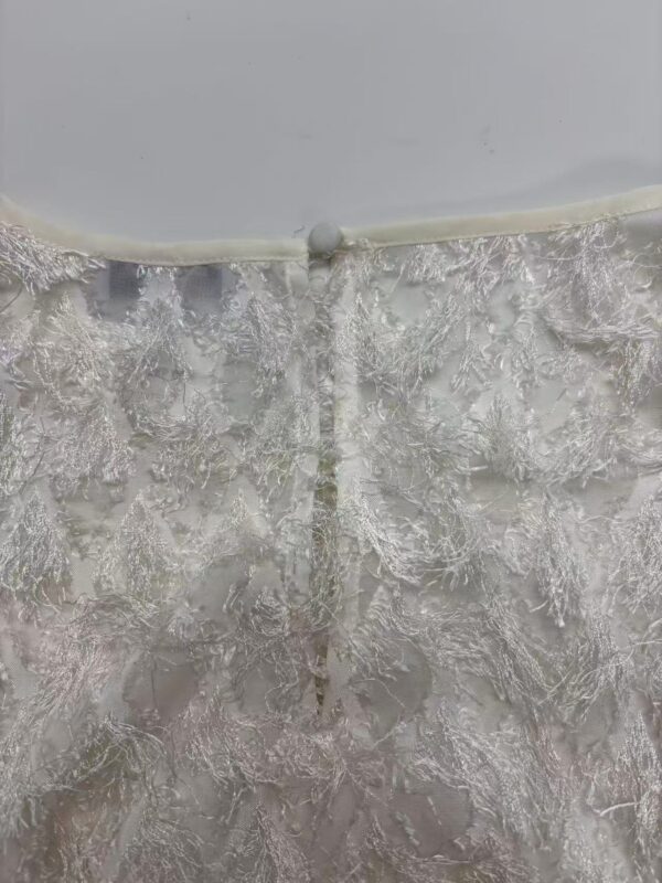 Close-up of intricate lace embroidery on a wedding dress with a delicate button closure at the back.