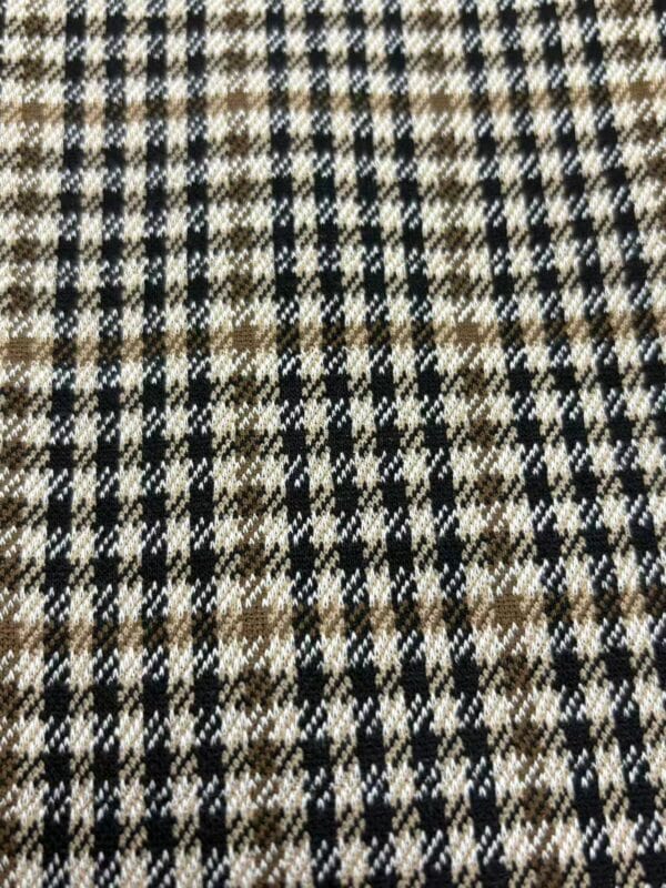 Close-up of checkered wool fabric in black, white, and brown tones, ideal for stylish clothing and accessories.