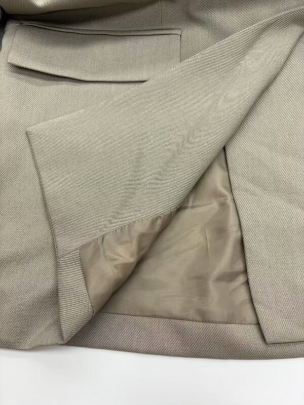 Close-up of beige suit fabric showing detailed texture and lining, ideal for formal wear or business attire.