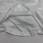Close-up of a white lace dress with satin lining, showcasing intricate lace patterns and smooth fabric for stylish fashion wear.