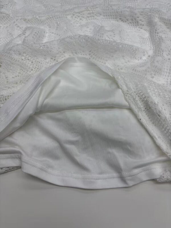 Close-up of a white lace dress with satin lining, showcasing intricate lace patterns and smooth fabric for stylish fashion wear.