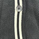 Detailed view of a dark gray knit cardigan featuring white and black striped trim and gray buttons, showcasing high-quality fabric and craftsmanship.