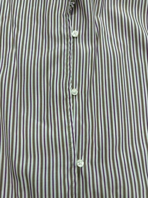 Close-up of a men's dress shirt with vertical stripes in white, purple, and green, featuring white buttons along the front placket.