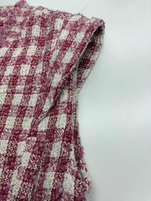 Close-up of pink and white checkered fabric with textured pattern, suitable for fashion or home decor projects.