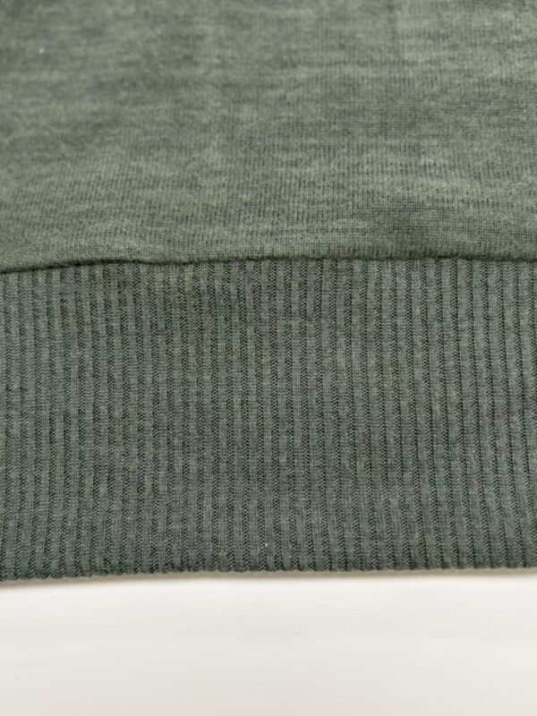 Close-up of green fabric with two different textures, one smooth and the other ribbed, suitable for clothing or upholstery.