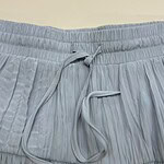 Close-up of light blue pleated lounge pants with an elastic waistband and drawstring for comfortable fit.