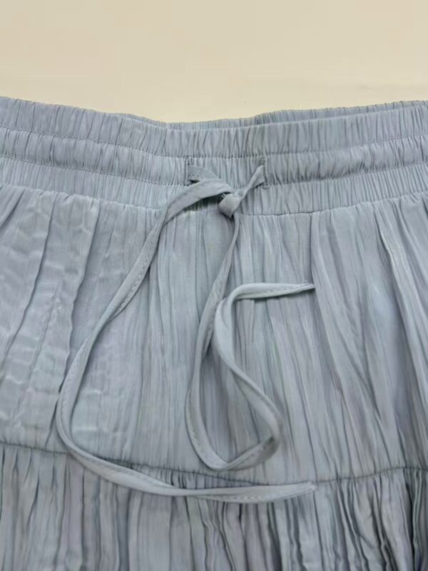 Close-up of light blue pleated lounge pants with an elastic waistband and drawstring for comfortable fit.