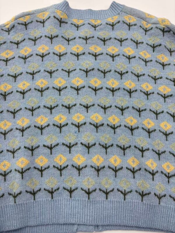 Light blue knitted sweater featuring a repeating pattern of yellow and black floral motifs, perfect for casual wear and cold weather.