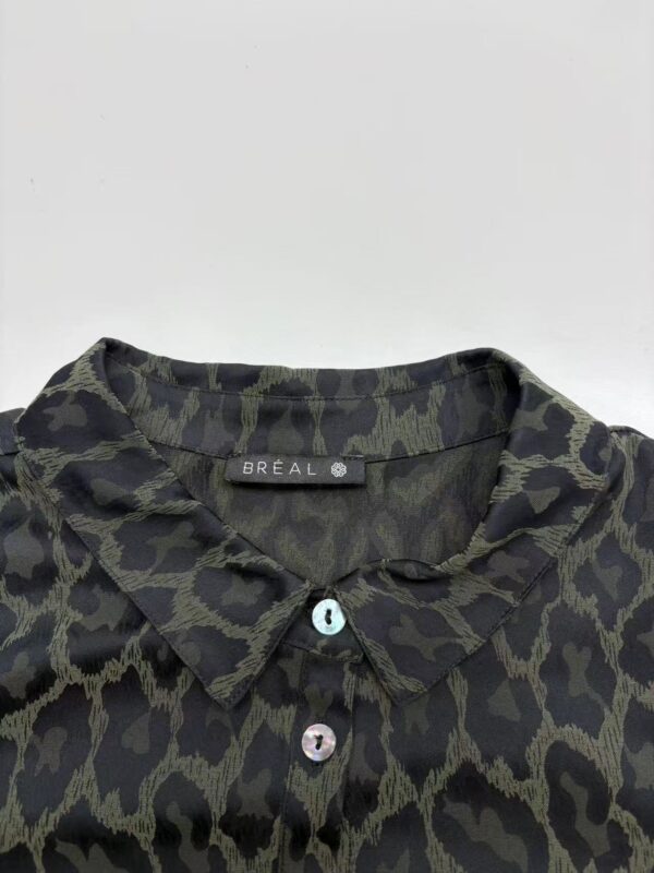 Close-up of a stylish black and olive green animal print shirt with a collar and buttons, perfect for casual or chic outfits.