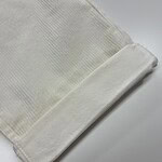 Close-up of a soft, white towel with a textured pattern, neatly folded on a clean surface, ideal for bathroom or spa settings.