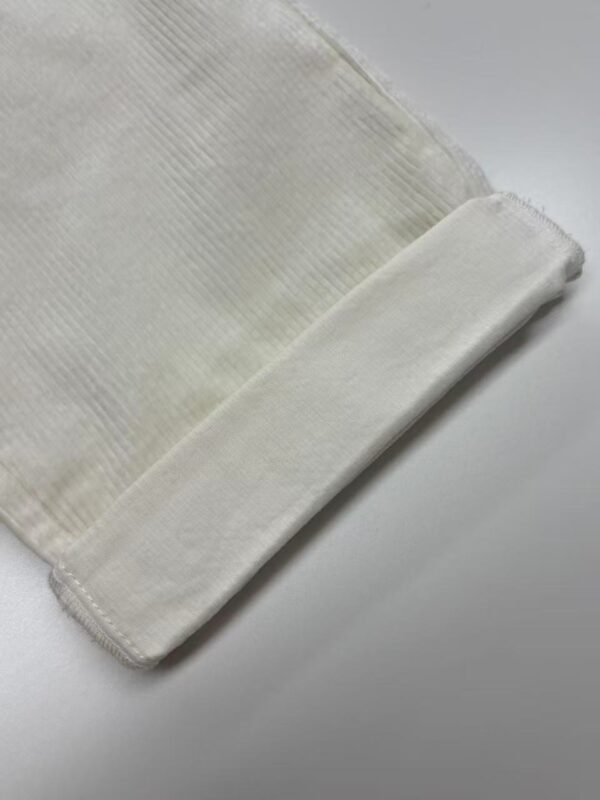 Close-up of a soft, white towel with a textured pattern, neatly folded on a clean surface, ideal for bathroom or spa settings.