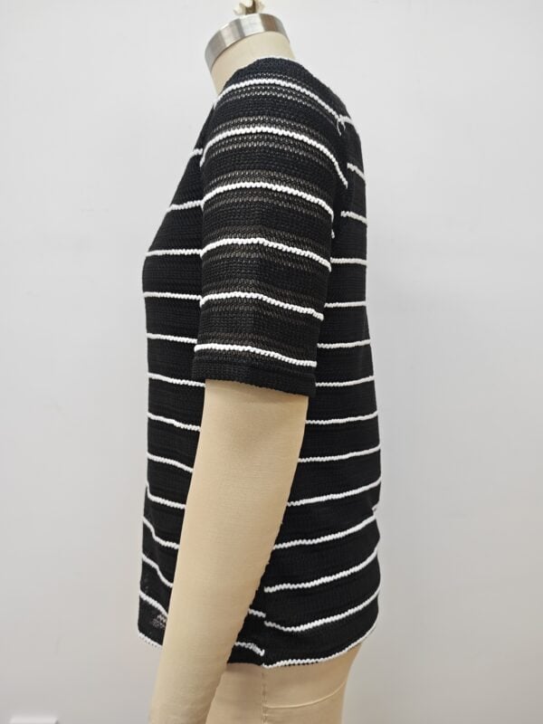 Close-up of a black and white striped knit sweater displayed on a mannequin, showcasing the textured fabric and pattern.