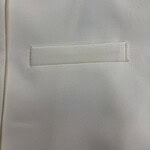 Close-up of a white blazer with a sleek, minimalist pocket design, perfect for formal or business attire.