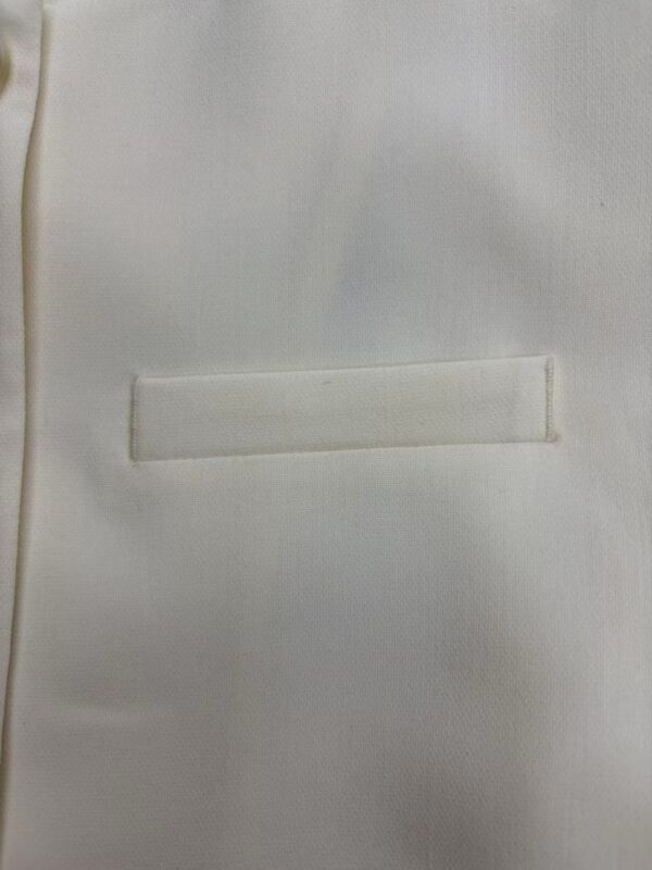 Close-up of a white blazer with a sleek, minimalist pocket design, perfect for formal or business attire.