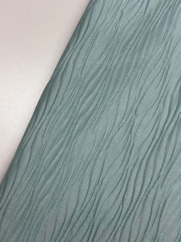 Close-up of soft green fabric with a textured, wavy pattern, ideal for fashion and apparel design.