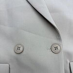 Close-up of a light gray women's blazer with two buttons and a lapel, showcasing tailored fashion and professional style.