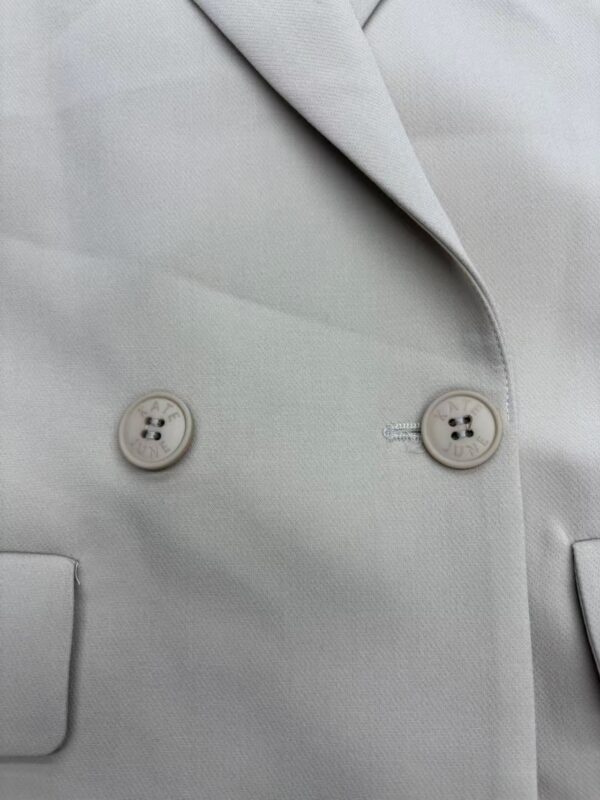 Close-up of a light gray women's blazer with two buttons and a lapel, showcasing tailored fashion and professional style.