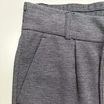 Close-up of women's tailored dress pants with a textured pattern, featuring a waistband and side pocket, suitable for professional or formal wear.