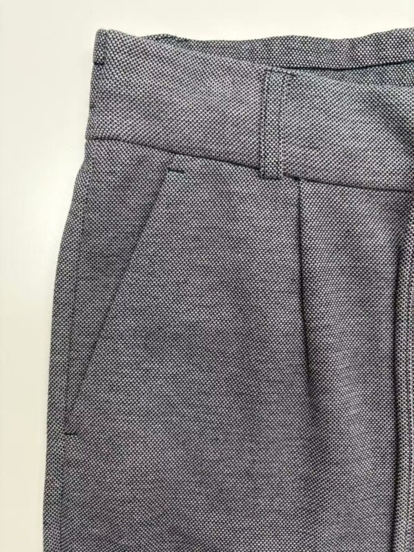 Close-up of women's tailored dress pants with a textured pattern, featuring a waistband and side pocket, suitable for professional or formal wear.