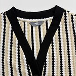 Close-up of a women's striped knit cardigan with black, white, and beige vertical patterns, featuring a V-neck and button closure.