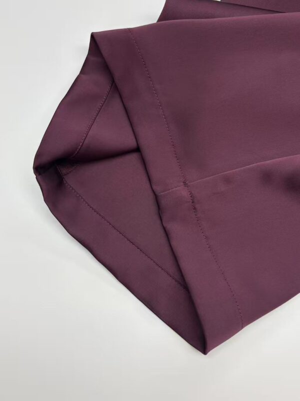 Close-up of burgundy fabric with detailed stitching, ideal for high-quality fashion garments and apparel.