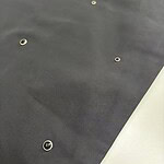 Close-up of black fabric with metal eyelets, suitable for fashion or accessory projects, showing texture and details.