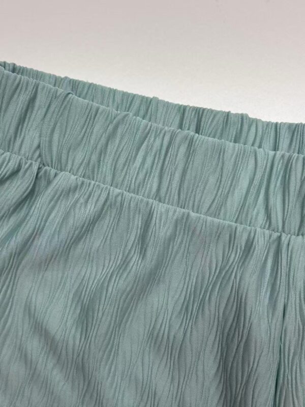 Close-up of a mint green pleated skirt with elastic waistband, showcasing textured fabric and stylish design for fashion-forward women.
