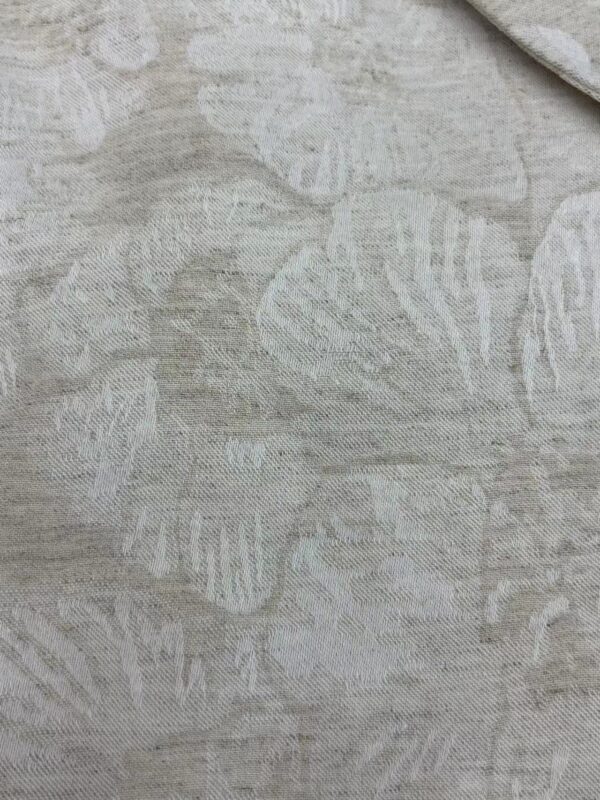 Close-up of light gray linen fabric with subtle leaf pattern, ideal for fashion and home decor projects.