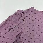 Close-up of a pink blouse with purple heart patterns and puffed sleeves, perfect for casual or semi-formal wear.