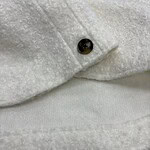 Close-up of a white wool coat featuring black buttons, showcasing high-quality fabric and craftsmanship, perfect for stylish winter wear.