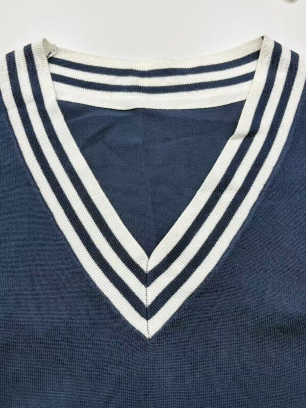 Close-up of a navy blue V-neck sweater featuring white and navy striped collar, showcasing stylish casual fashion for men and women.
