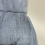Close-up of a light blue pleated dress with a cinched waist, showcasing soft fabric and detailed pleats, perfect for fashion and style enthusiasts.