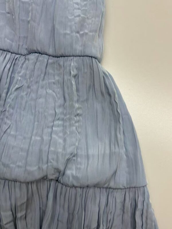 Close-up of a light blue pleated dress with a cinched waist, showcasing soft fabric and detailed pleats, perfect for fashion and style enthusiasts.