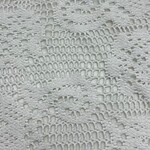 Close-up of intricate white lace fabric with floral and swirl patterns, ideal for fashion and dressmaking.