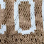 Close-up of a knitted fabric with a beer mug design in white on a brown background.