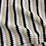 Close-up of a knitted fabric with black, white, and beige vertical stripes, showcasing a textured pattern suitable for clothing or accessories.