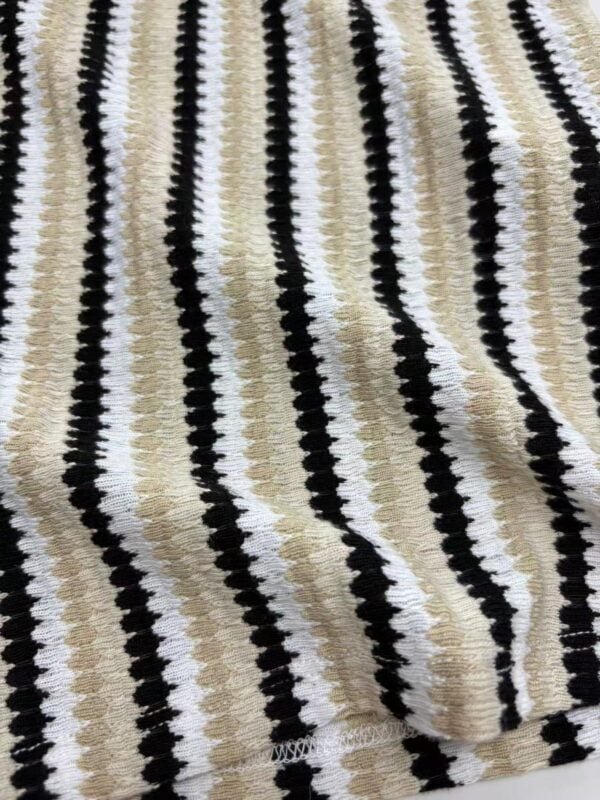 Close-up of a knitted fabric with black, white, and beige vertical stripes, showcasing a textured pattern suitable for clothing or accessories.