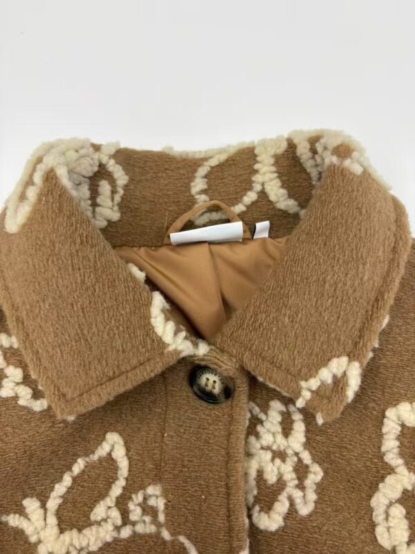 Close-up of a brown wool coat with white embroidered floral patterns, featuring a collar and a button closure, perfect for fall and winter fashion.
