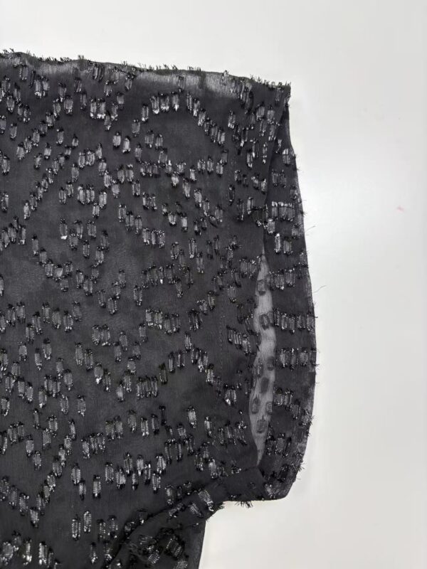 Close-up of black fabric adorned with intricate beadwork, perfect for high-end fashion designs and evening wear.