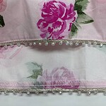 Close-up of floral fabric featuring pink and purple flowers with pearl embellishments along the edge, ideal for fashion and textile design.