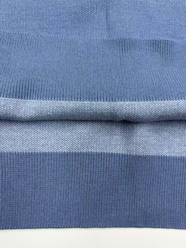 Close-up of blue fabric with detailed knit pattern, showcasing texture and quality suitable for fashion and clothing manufacturing.