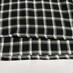 Close-up of black and white checkered fabric with detailed stitching and pattern, suitable for fashion or upholstery use.