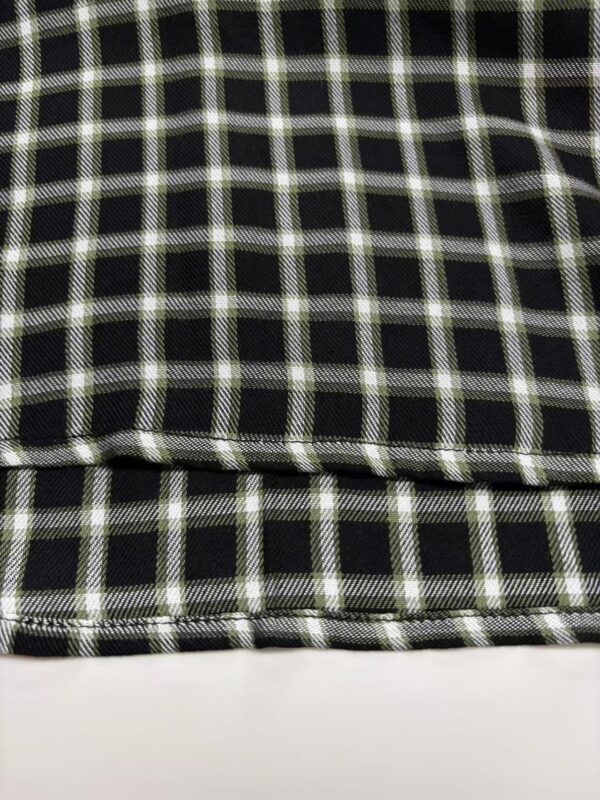 Close-up of black and white checkered fabric with detailed stitching and pattern, suitable for fashion or upholstery use.