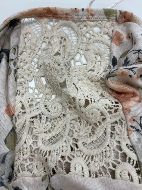 Close-up of intricate cream-colored lace fabric with floral and geometric patterns, suitable for fashion and clothing embellishments.