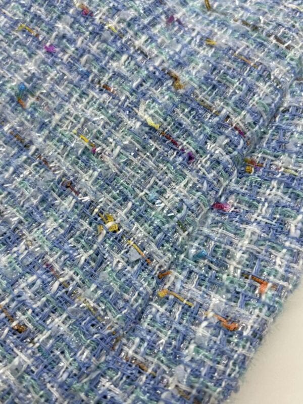 Close-up of vibrant multicolored tweed fabric showcasing intricate woven texture, ideal for high-end fashion garments and accessories.