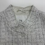 Close-up of a silver tweed women's jacket with a V-neckline and button closure, showcasing textured fabric and stylish design.